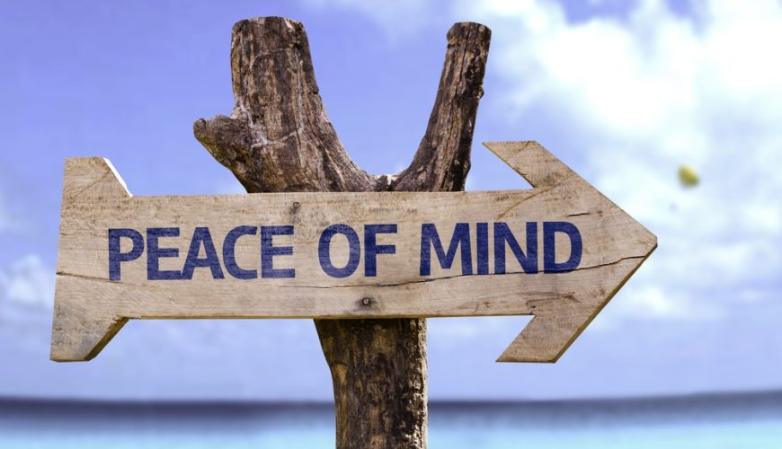 Wooden sign with the phrase 'Peace of Mind' on a beach.