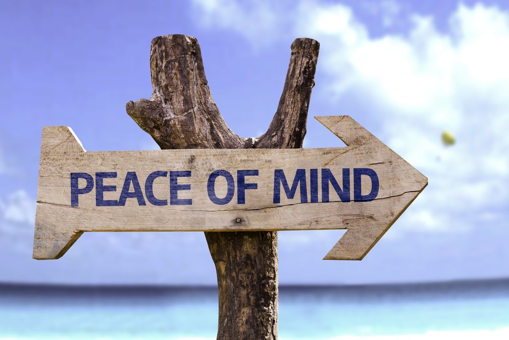 Wooden sign with the phrase 'Peace of Mind' on a beach.