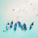 Aerial view of beach with longtail boats and a sandbar
