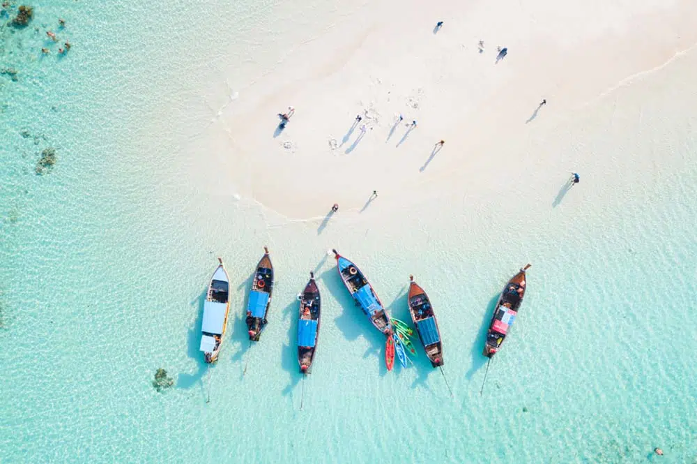Aerial view of beach with longtail boats and a sandbar