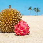 Durian and dragon fruit on the sand at the shore.