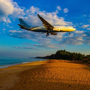 a plane flies over the beach in Phuket on its way in to land