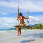 A woman sits on a swing on the White Sand Beach in Phuket