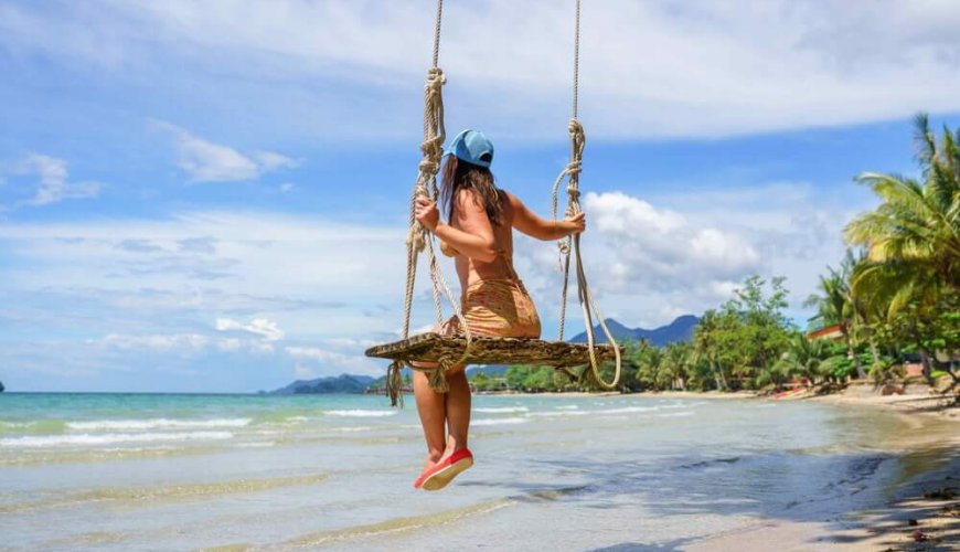 A woman sits on a swing on the White Sand Beach in Phuket